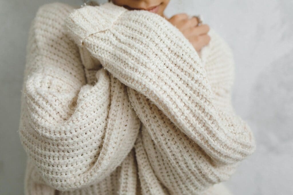 Cozy, cream, oversized fisherman's sweater close-up on unseen woman.