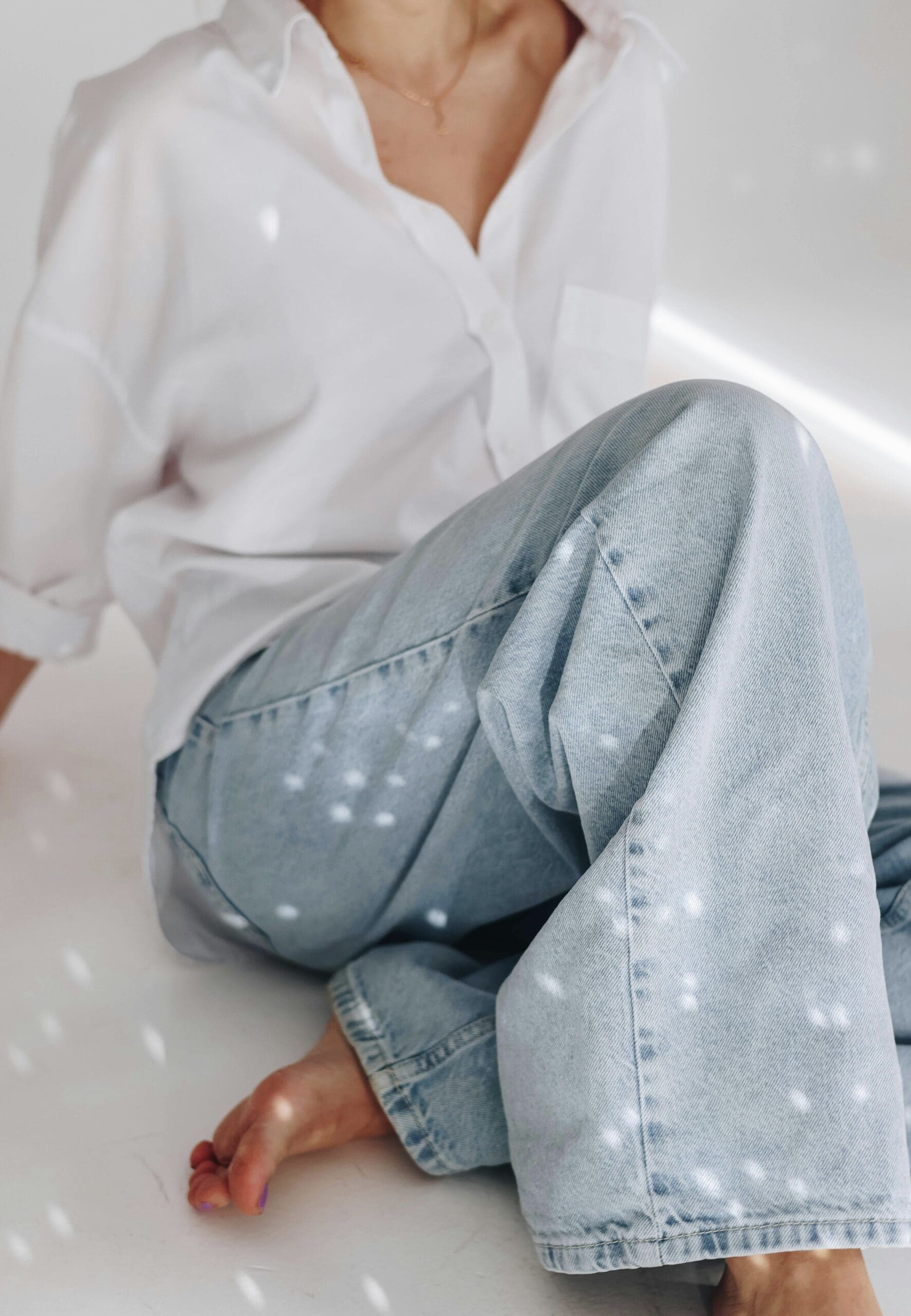Loose jeans and oversized white shirt on woman just out of view. Airy and light.