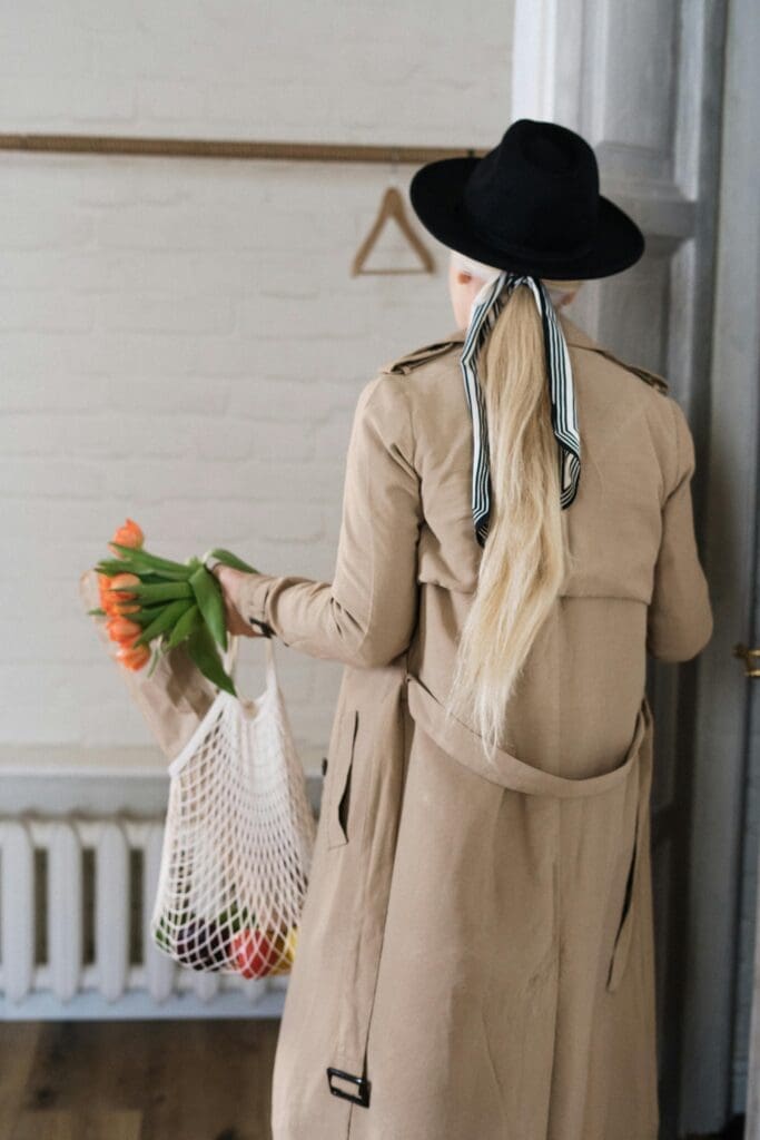 Woman in trench coat with scarf in hair, view from the back.